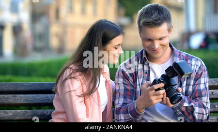 Photographer showing young model photos on camera after photoshoot in park Stock Photo