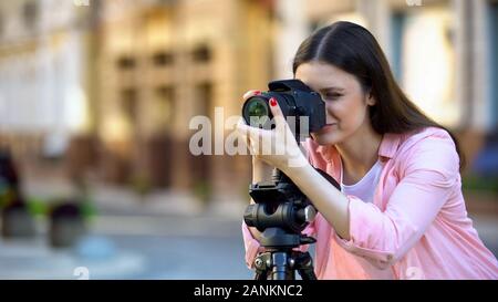 Professional female photographer focusing camera objective, photo shooting Stock Photo