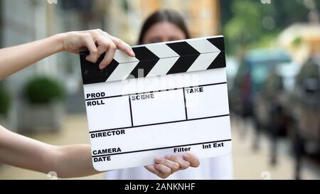 Hands holding clapperboard in front of young woman, movie scene, production Stock Photo