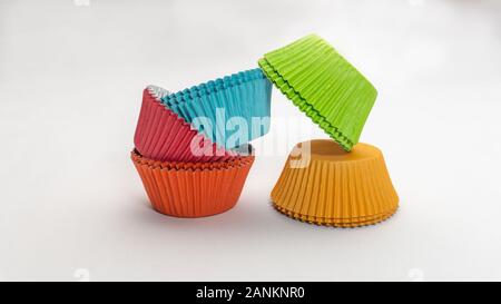 Wide shot of colorful cupcake wrappers stacked up in two piles on a white background Stock Photo