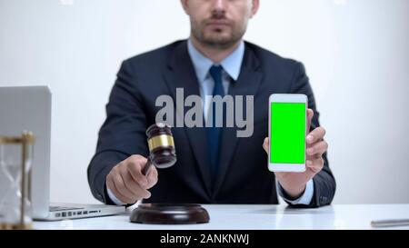 Attorney banging gavel holding cellphone, constitutional law in mobile apps Stock Photo