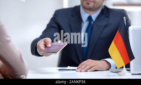 German consular officer giving passport to woman, refugee visa, asylum status Stock Photo