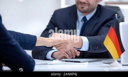 German boss signing employment contract with immigrant employee, shaking hand Stock Photo