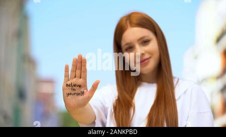 Young female showing palm with believe in yourself phrase, self-confidence Stock Photo