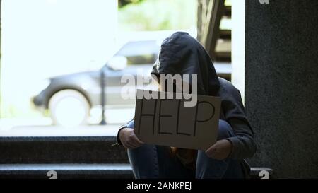 Teenage girl showing help sign sitting on stairs, lost in life, needs support Stock Photo