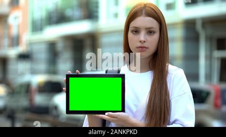 Serious girl holding green screen tablet, online courses, free trial lesson Stock Photo