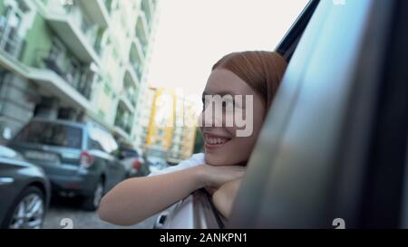 Happy girl looking through window, enjoying city attractions travelling by car Stock Photo
