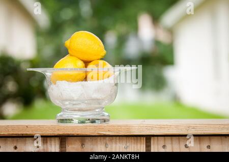 A bowl of fresh lemons sitting on a tabletop Stock Photo