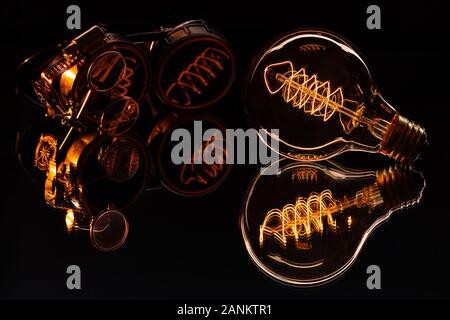 A Very crisp steampunk shot of a pair of goggles and a lit edison lightbulb on a reflective surface.  Warm tones and sharp focus. Stock Photo