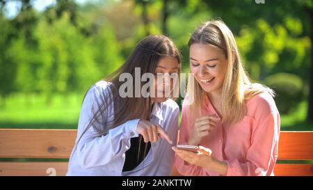 Happy female friends having fun laughing at internet photo, friendship leisure Stock Photo