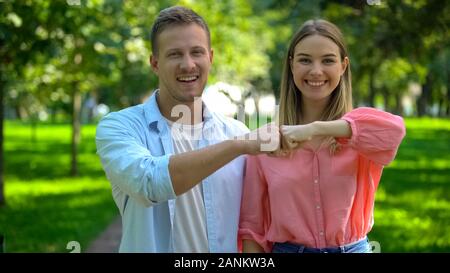 Smiling man and woman bumping fists at park, good old friendship, togetherness Stock Photo