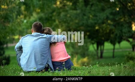 Loving male and female hugging sitting on grass in park, couple togetherness Stock Photo
