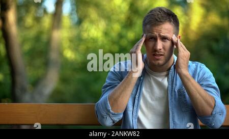 Stressed man massaging temples feeling headache, exhaustion symptom, pain Stock Photo