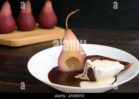 Red Wine Poached Pears with Dark Chocolate & Vanilla Cream: Bosc pear poached in red wine, sliced in half, and served with chocolate sauce Stock Photo