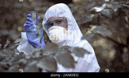 Lab worker holding biohazard test tube, dangerous virus, global threat pollution Stock Photo