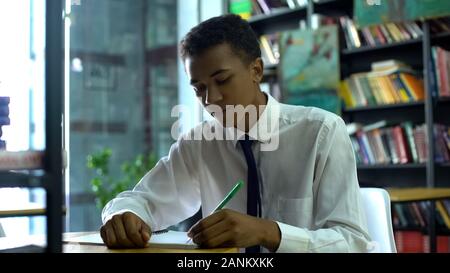 Afro-American male student preparing for test at school library, education Stock Photo
