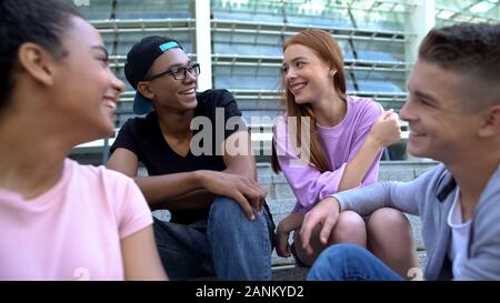 Male and female millennials smiling each other sitting aside, romantic relations Stock Photo