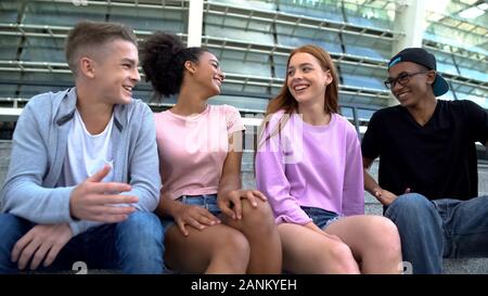 Smiling college students sitting together stairs, laughing having fun generation Stock Photo