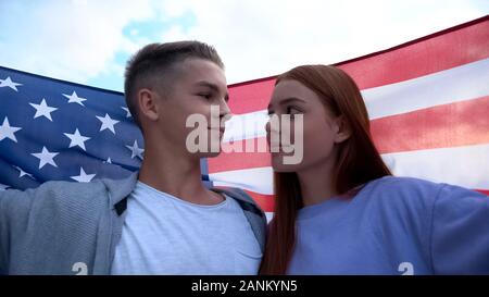Loving students couple looking each other, holding american flag, young patriots Stock Photo