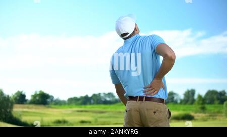 Athletic man golfer suffering sharp lower back pain, sport trauma, health Stock Photo
