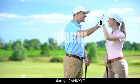 Joyful golfers with clubs giving high-five after successful sport championship Stock Photo