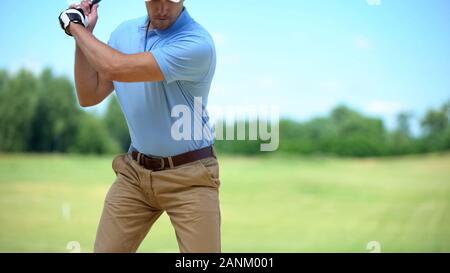 Serious golfer hitting ball in backswing position, preparing for competition Stock Photo