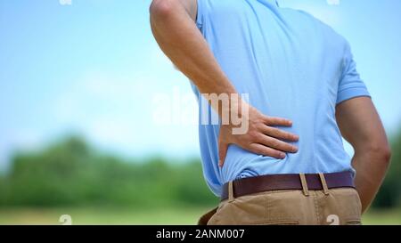 Male feeling sharp lower back pain outdoor, health and problems, medicine Stock Photo