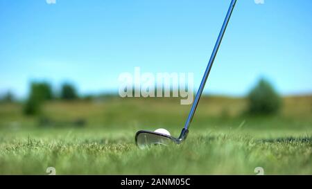 Iron golf club hitting white ball on course, professional sport, elite hobby Stock Photo