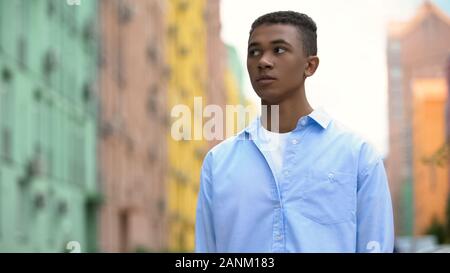 Scared mixed-race boy nervously waiting for girlfriend outdoor, first date Stock Photo
