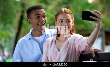 Smiling teenage couple having fun, making selfie photos on smartphone camera Stock Photo