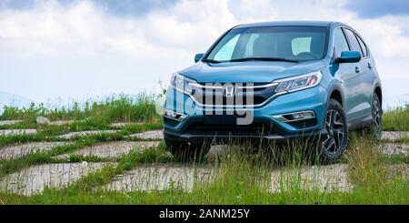 mnt. runa, ukraine - JUN 22, 2019: blue suv on a paved meadow. popular AWD vehicle in nature scenery. stormy weather with cloudy sky. take your family Stock Photo