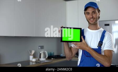 Handyman showing tablet with green screen, ad of maintenance work, service Stock Photo