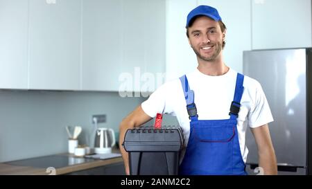 Handyman holding tools standing in kitchen, professional plumbing services Stock Photo
