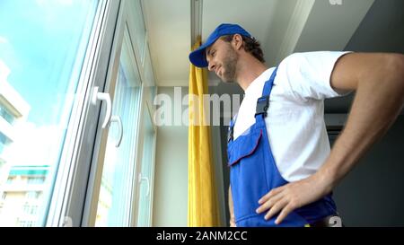 Smiling repairman satisfied with window system installation, quality service Stock Photo