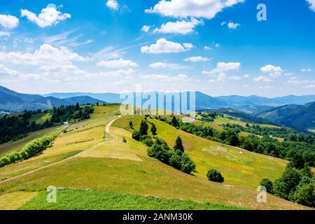 mountain rural landscape in summertime. country path winding off in to the distant ridge. rolling hills with grass fields and meadows. calm sunny weat Stock Photo