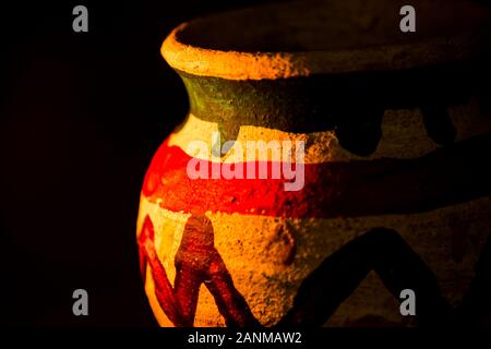 Handcrafted earthen pot again dark background. Clay vase made out of mud on dark background. Stock Photo