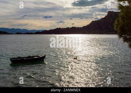 Small boat in Vouliagmeni lake near Loutraki at sunset, Greece Stock Photo