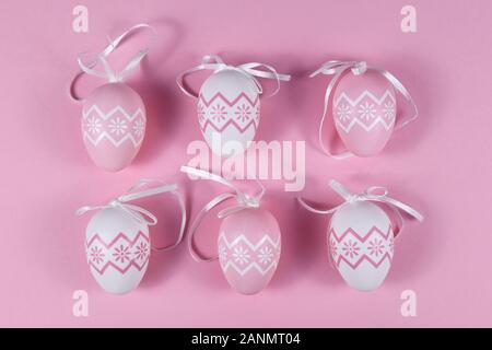 Top view on white and pink easter eggs in two rows with ribbons on pink background Stock Photo