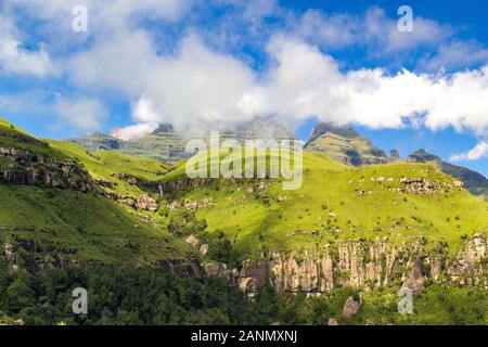 Monk's Cowl, Champagne Castle and Cathkin Peak shrouded in some clouds on a sunny summer day, green landscape with steep mountains and a waterfall, Dr Stock Photo