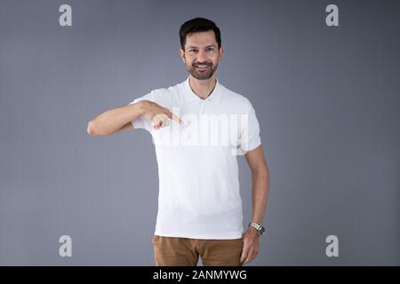 Smiling Man In Casuals Standing Pointing At T-Shirt Stock Photo