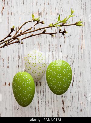 Easter eggs hanging on a branch against the wooden background Stock Photo