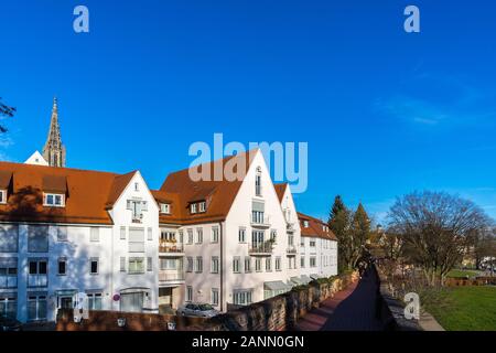 Ulm, Germany, December 29, 2019, Ancient city wall and danube riverside with view to old town and church steeple of minster cathedral, tourists walk a Stock Photo