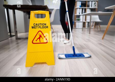 Female Janitor Mopping Floor In Modern Office Stock Photo