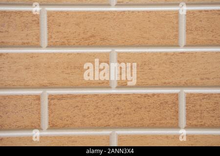 Beige textured brick interior or exterior wall with white grout. A concept or background for interior design, construction, DIY, or building. Stock Photo