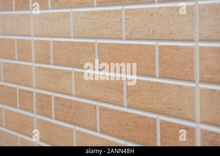 Angled view of Beige textured brick interior or exterior wall with white grout. A concept or background for interior design, construction, DIY, or bui Stock Photo