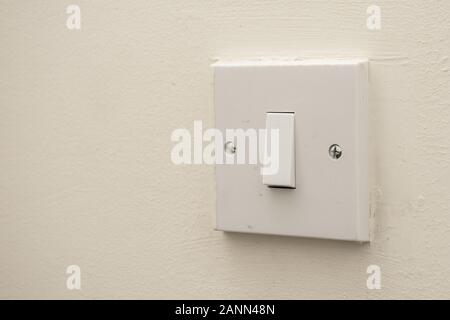 A simple white electrical light switch on a white wall. Industrial, residential or DIY construction concepts. Stock Photo