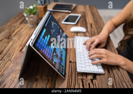 Close-up Of A Businesswoman's Hand Analyzing Graph On Laptop At Workplace Stock Photo