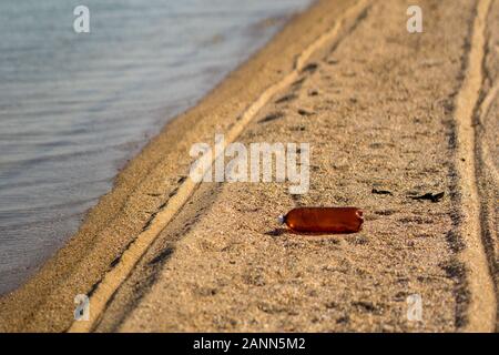 Empty plastic bottle lying on the sandy beach. Environmental pollution Stock Photo