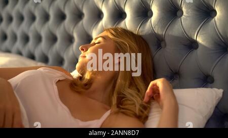 Sunbeams on female face lying in bed, beginning of good day, happiness closeup Stock Photo