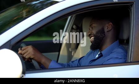 Cheerful adult afro-american man driving new auto, enjoying trip and smiling Stock Photo
